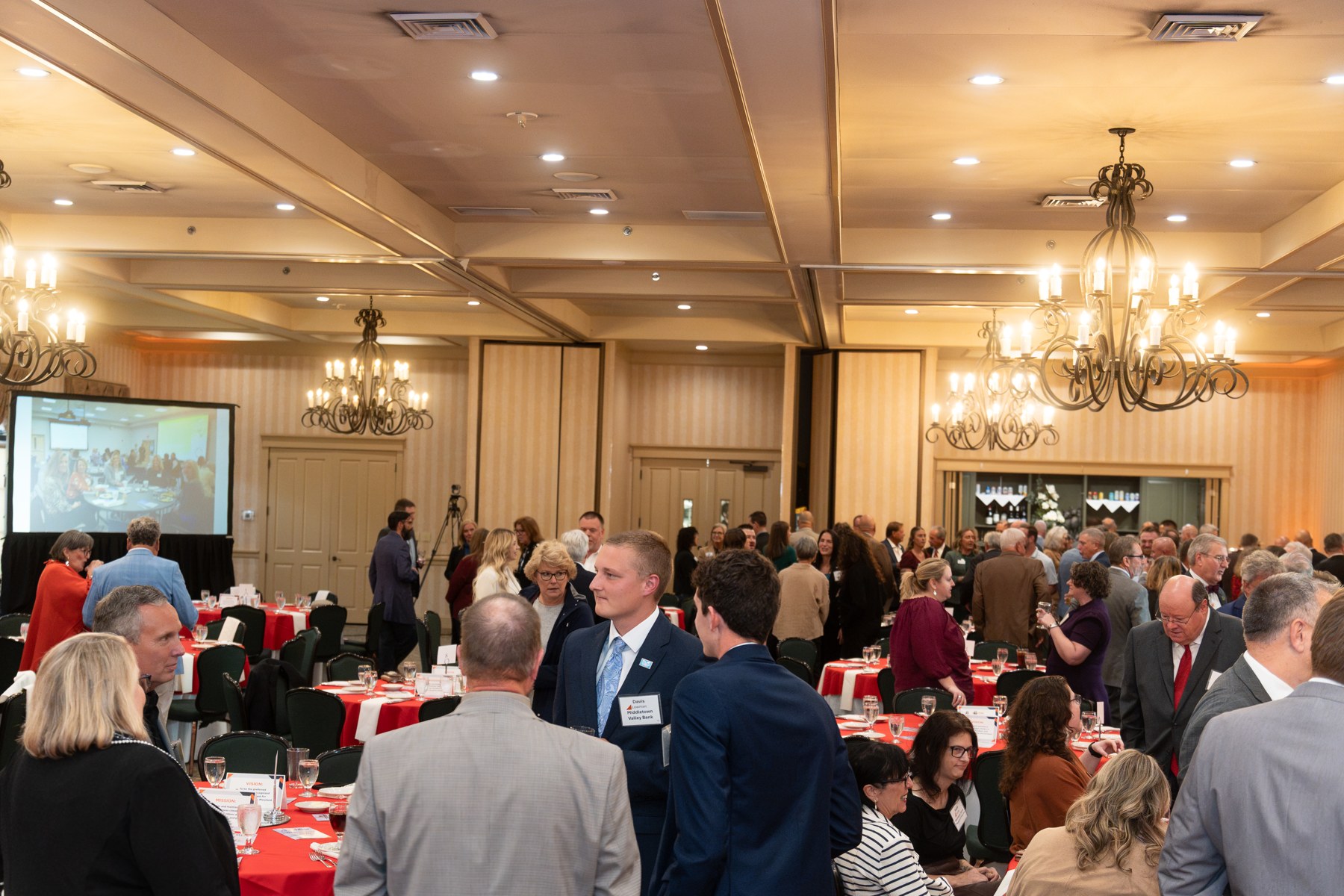 Attendees standing together at tables in the ballroom