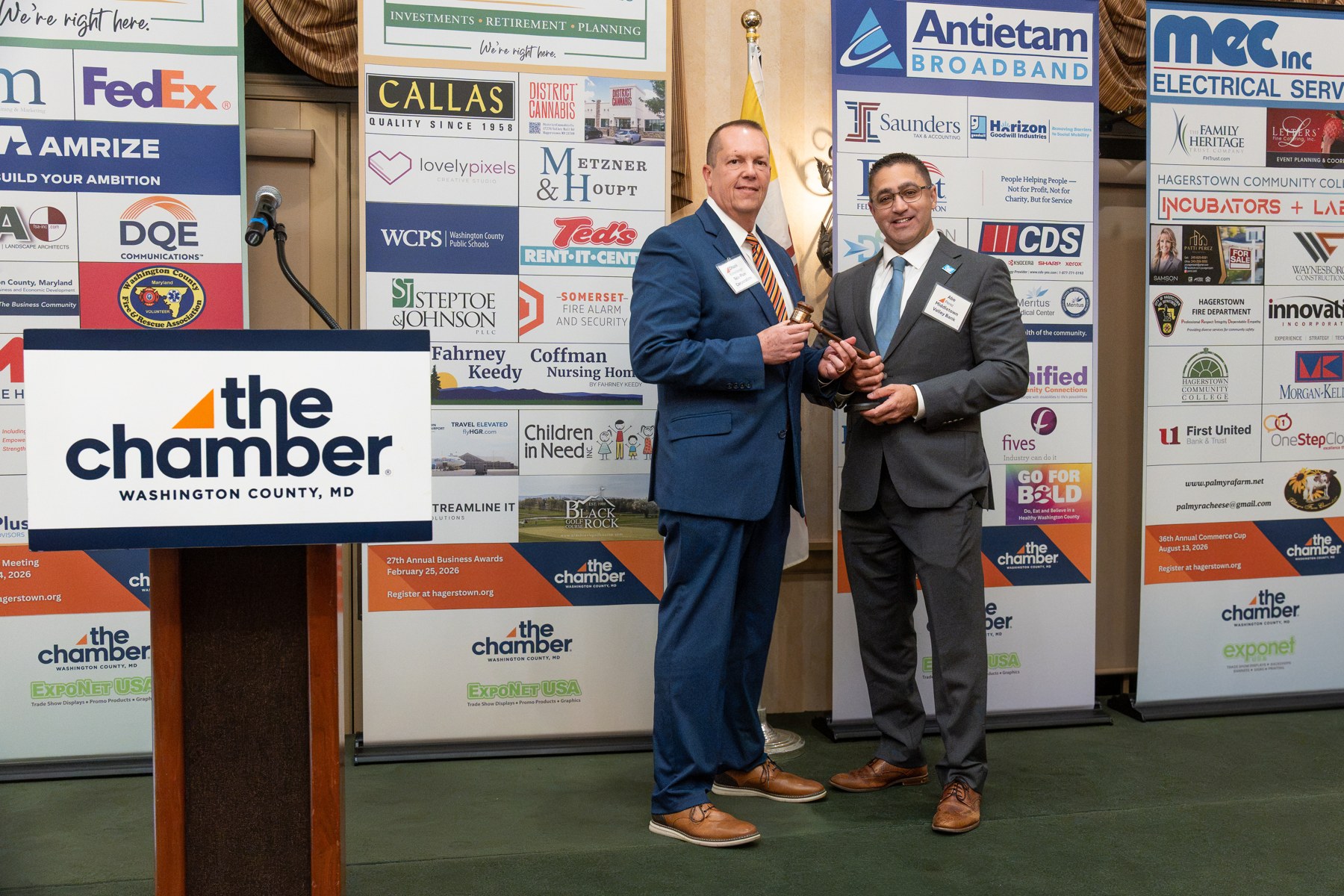Presenters passing the gavel on stage at the Chamber Annual Meeting