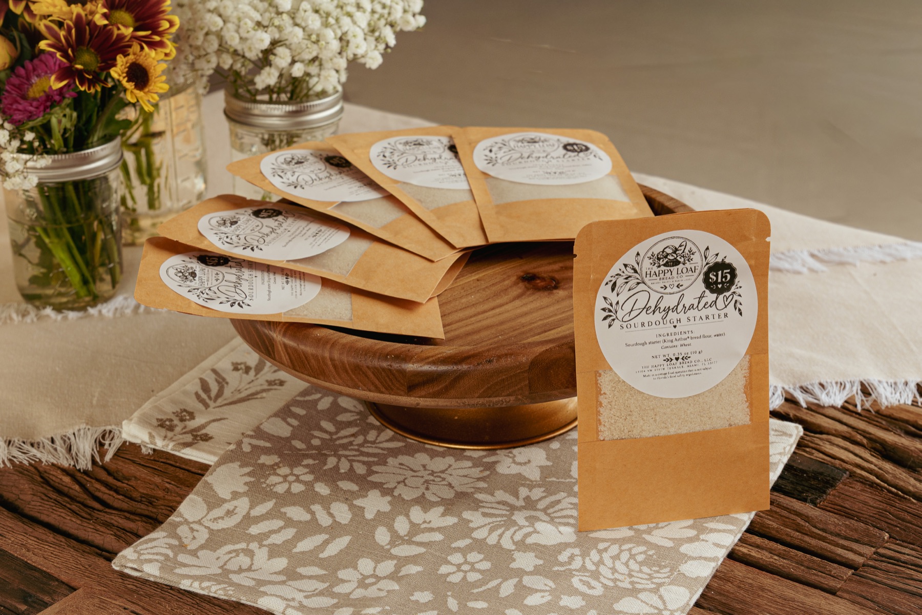 Happy Loaf packages labeled Dehydrated Sourdough Starter on a wooden stand.
