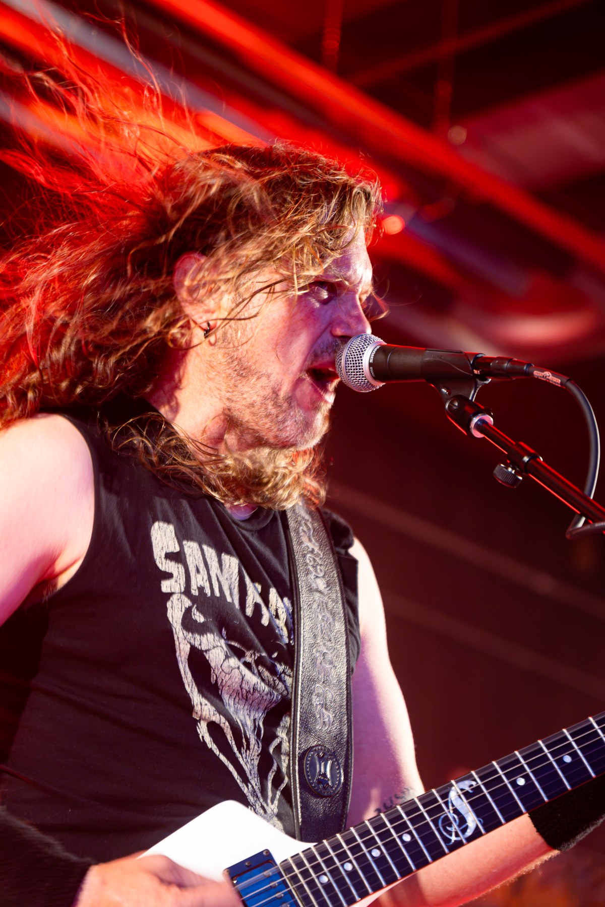 A singer and guitarist performing under red stage lights