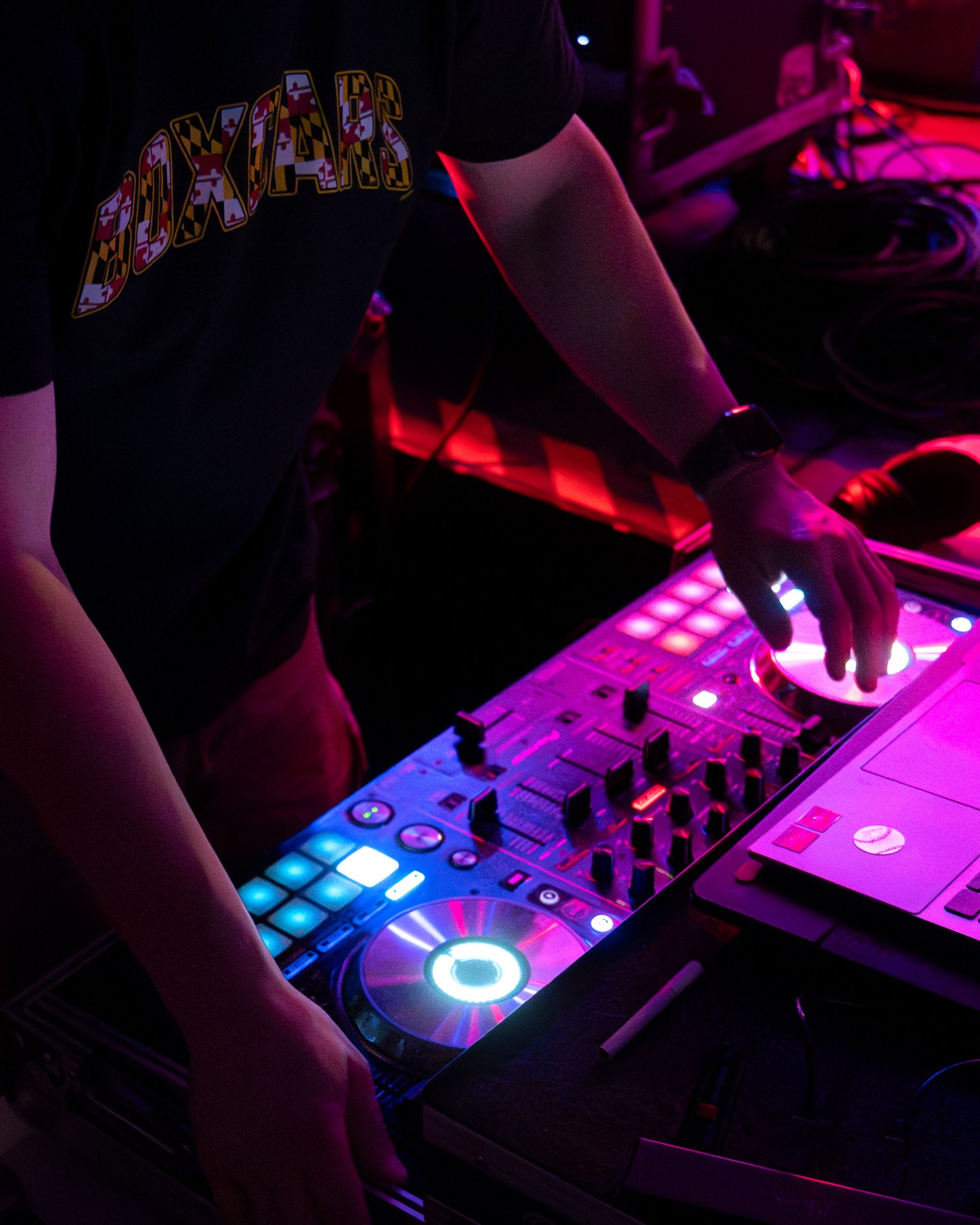 A DJ working at the controller under colored lights