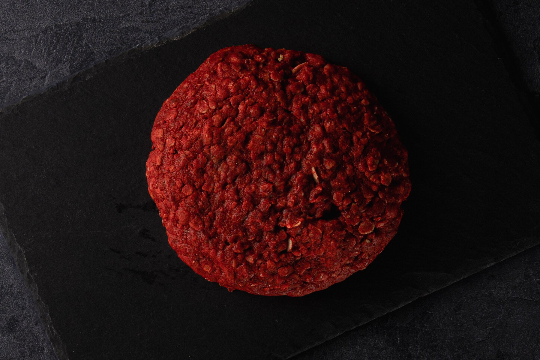 A red cookie photographed against a dark backdrop